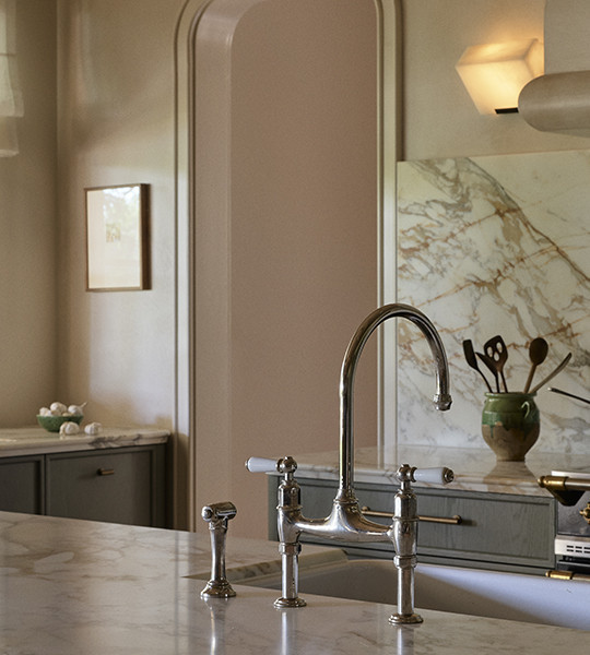 Best brass kitchen tap, traditional bridge tap style with rounded spout and lever handles, over a butler sink.