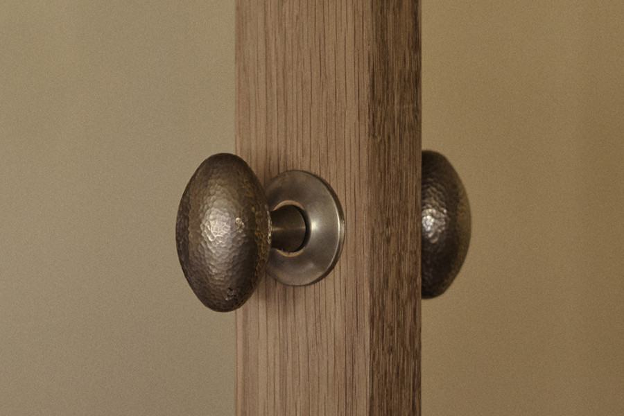 Joseph Giles intricate hammered brass oval doorknobs from the In Residence on a timber door.