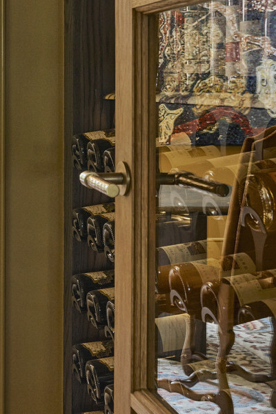 A door with a Joseph Giles hammered brass oval doorknob from In Residence opens into a wine cupboard. 