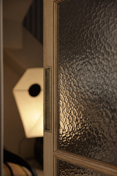 A sliding timber and glass door with a Joseph Giles rectangular solid brass recessed pull from In Residence.