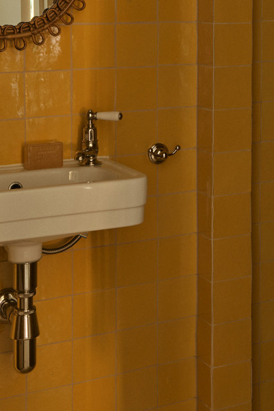A powder-room with orange square tiles with mini white Deco style Soho basin from In Residence and Polished Nickel classical Perrin & Rowe pillar taps.