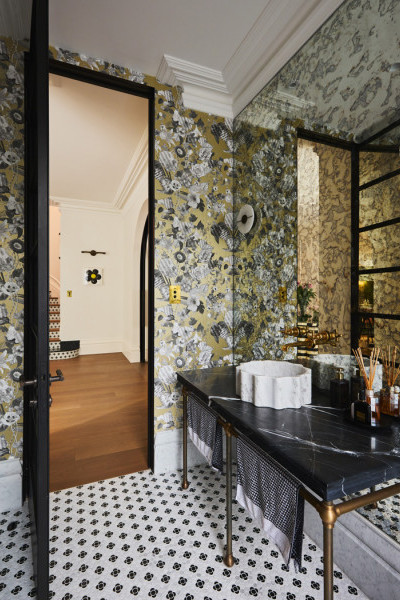 Powder room featuring polished brass tapware, grey Rockwell toilet pan, black marble vanity, and champagne floral wallpaper creating a bold yet elegant design