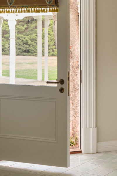 Laundry with soft cream and warm beige tones, Joseph Giles brass hanging rails, Perrin & Rowe tapware, and Armac Martin cabinetry opening toward the garden.